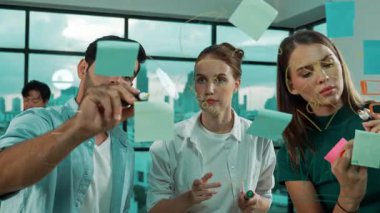 Profesyonel iş adamları beyin fırtınası yapıyor, fikir paylaşıyor, düşünüyor yetenekli erkek liderler cam duvarda yapışkan notlar yazarken. Yetenekli yönetici ofisteki cam duvara iş planı koymuş. İzleme