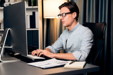 Akıllı iş adamı iş paragrafı dinamik pazarlama analizi planını analiz ediyor. Kağıt kağıtları ve bilgisayar monitörü raporlarını gece evdeki belge verileriyle karşılaştırmak için hazırlıyor. Bireysel.