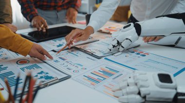 Değişik çizelgeler ve modern bir ofis masasıyla ilgili raporlarla çevrili iş verilerini analiz eden dinamik bir işbirliği sahnesi. Noogenesis