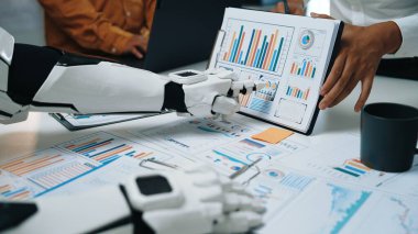 Profesyoneller tartışmalara girerken, fütüristik bir robot kolu iş haritalarını sergiliyor. Bu sahne veri analizinde teknoloji ve insan işbirliğinin kesişimini vurgular. Noogenesis
