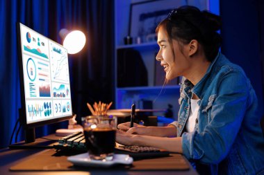 Gülümseyen genç, güzel Asyalı yaratıcı satış hedefi raporunun kar tablosuna bakıyor ve notlar üzerine notlar yazarak neon ışığı gecesinde yeni bir strateji pazarı projesine yatırım yapmayı planlıyor. Taktik.