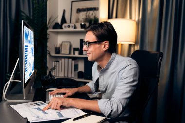 Akıllı iş adamı iş paragrafı dinamik pazarlama analizi planını analiz ediyor. Kağıt kağıtları ve bilgisayar monitörü raporlarını gece evdeki belge verileriyle karşılaştırmak için hazırlıyor. Bireysel.