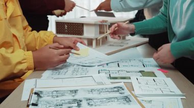 Modern ofis ortamında mimari planlar ve teknik çizimler üzerinde aktif olarak işbirliği yapan profesyonellerin dinamik bir sahnesi, takım çalışması ve yaratıcılığı gözler önüne seriyor. SACTR
