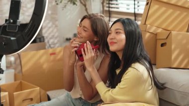 Satıcı çevrimiçi platformu kullanarak canlı yayın yaparken ürünü incelemek ve satmak için birlikte çalışıyor. Zeki Asyalı girişimci soruları cevaplarken ürün gösteriyor. Medya. Yan görüş. Myrmidon.