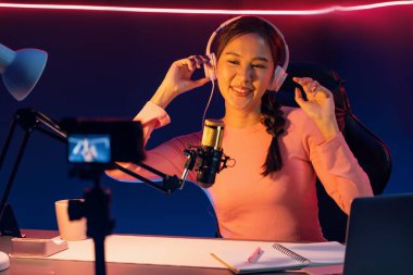 Yaratıcı yayın kanalı sosyal medyada pozitif podcasttaki dinleyicilerle birlikte müziği dinliyor, pastel renkli kulaklıklar takıyor, neon stüdyodaki kameraların mikrofon kayıtlarını kullanıyor. Taktik.