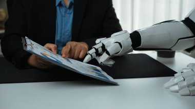 Bir insan ve robotu modern çalışma alanlarında insan zekasının ve robot yardımının füzyonunu vurgulayan bir iş tartışmasında gösteren ilgi çekici bir görüntü. Noogenesis