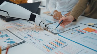 Robotik bir el, çizelgeler ve grafiklerle dolu iş belgelerini analiz etmede, modern teknolojilerin işbirlikçi ortamlardaki rolünü göstermede bir insana yardım eder. Noogenesis