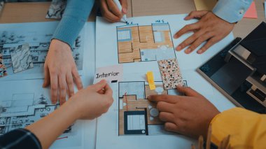 İç tasarım, çizimler, renk örnekleri ve planlar gözden geçirilerek el ele tutuşan eller görüntüsü. Dinamik yaratıcı çalışma alanı tasarım takım çalışmasını gösterir. SACTR