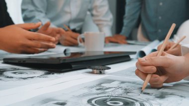 Nişanlı takım üyeleri proje planlarını bir işbirliği toplantısı sırasında tartışırlar. Çizimler, dizüstü bilgisayar ve kahvenin olduğu yaratıcı bir çalışma alanı üretkenliği ve yeniliği teşvik eder. SACTR