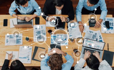 Bir iş toplantısına katılan dinamik bir ekip, dizüstü bilgisayarlardaki veri ve çizelgeleri analiz ediyor, bilgilendirilmiş karar verme konusunda işbirliği ve yenilikçi stratejiler sergiliyor. Dostluk