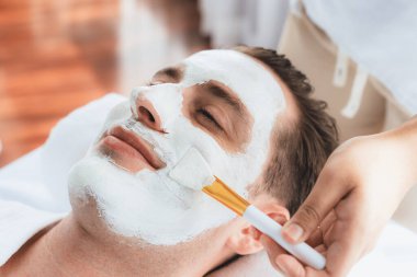 Kaplıca salonunun sakin atmosferi, insan müşterisi modern gün ışığında lüks yüz kremi masajıyla kendini yenileme zevkine kapılıyor. Yüz bakımı ve güzellik konsepti. Sessiz.