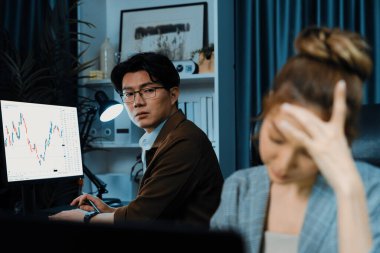 Stresli iş kadını, arka planda çalışan iş arkadaşıyla e-posta yoluyla bilgisayar borsasına bakıyor. Akşamları modern ofis binasında zarar karıyla ilgili soru sormak için konuşuyorlar. İnfobahn.