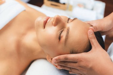 Kafkasyalı kadın stres önleyici kafa masajından ve lüks tatil beldesi ya da otel spa salonundaki modern ışık ortamında yüz güzelliği eğlencelerini şımartmaktan hoşlanıyor. Sessiz.