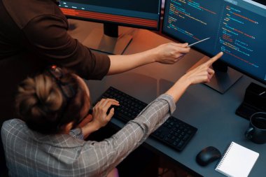 Akıllı web sitesi geliştirme kodlayıcı sistemi ile tartışan IT geliştiricilerinin üst görüşü modern ofisteki neon ışık odasında iki ekran bilgi teknolojisini çevrimiçi çalıştırıyor. İnfobahn.