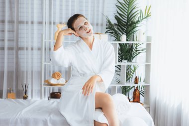 Kaplıca salonunun sakin, modern gün ışığı atmosferi, kadın müşteri poz veriyor ve yüz maskesi ile gençleştiriyor. Yüz bakımı ve güzellik kozmetolojisi prosedürü. Sessiz.