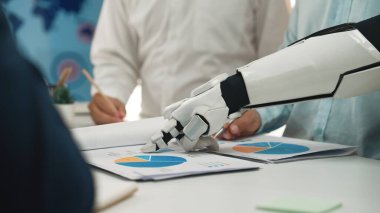 Bir robot kol, veri analizi ve modern ofis uygulamalarında teknolojinin entegrasyonunu vurgulayan bir iş toplantısında profesyonellere yardımcı olur. Noogenesis