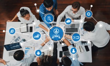 Çeşitli bir ekip modern bir çalışma alanında CRM stratejileri ve veri çözümlerini tartışarak işbirliği yapıyor. Atmosfer bağlılık ve yenilikçi yönetim tekniklerini yansıtıyor. Dostluk
