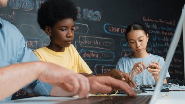 Genç öğrenci BTMM sınıfında öğretmenlik yaparken denetleyiciyi tamir ediyor. Akıllı kız elektronik alet ve karatahta kullanırken eğitmen el bilgisayarı. Öğretim.