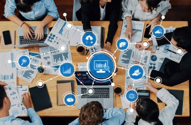 Çeşitli bir ekip veri raporları ve dijital grafiklerle kaplı bir masada işbirliği yaparak, profesyonel bir ortamda teknoloji ve takım çalışması yoluyla anlayışı geliştiriyor. Dostluk