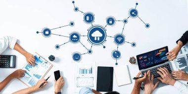 Ekip üyeleri veri analizi ve bilgi paylaşımı yaparken, çeşitli dijital araçlar ve bulut bağlantılarının yer aldığı işbirlikçi bir çalışma alanının tepeden aşağı bir görüntüsü. Dostluk