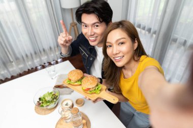 Gülümseyen ev sahibi aşçıların akıllı telefonuyla fotoğraf çekerken üst görüntüsü yemek programında çift hamburger tutarken sosyal medya kanalında ev yapımı salata tabağıyla kolaylıkla görülebiliyor. İnfobahn.