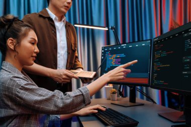 Bilgi teknolojisi geliştiricileri modern ofisteki neon ışık odasında verileri çevrimiçi olarak çalıştıran akıllı web sitesi geliştirme kodlayıcı sistemine işaret ediyorlar. İnfobahn.