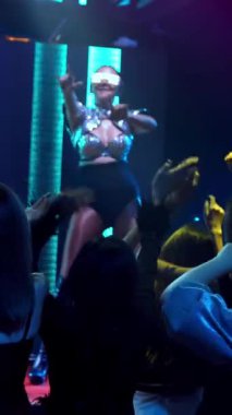 Bir grup insan disko gece kulübünde DJ 'in sahnede çaldığı müzikle dans ediyor. Yeni yıl partisi ve gece hayatı konsepti .