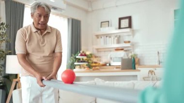 Yaşlı bir adam evde partneriyle top yuvarlama oyunu oynuyor, zihinsel ve fiziksel sağIık için el-göz koordinasyonu, odaklanma ve motor becerileri pratiği yapıyor. Sağlık hizmetleri konseptini engelliyor. Myrmidon.