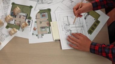 Mimari belge, ölçüm aracı ve ahşap blokların modern ofiste etrafa saçıldığı bir masa üzerinde yapı inşaatı ile ilgili mimar ve güvenlik mühendisi tartışması. Tanımlama.