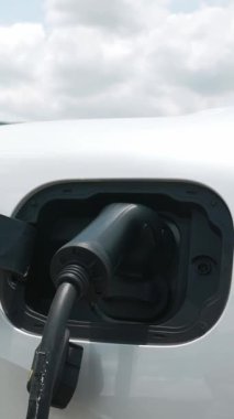 İlerici elektrikli araç konsepti, EV araba şarj istasyonu ile birlikte. Yeşil arazinin doğal arka planında göl ve yeşil tepe yenilenebilir enerjili eko-otomobilden temiz çevre için.