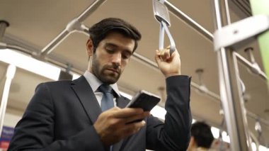 İş adamının elleri trende insanlarla çevriliyken telefona bakarken yakın çekim. Kafkas proje yöneticisi e-postaları kontrol ediyor, arka planı bulanık pazarlama stratejisi planlıyor. Sevinçli..