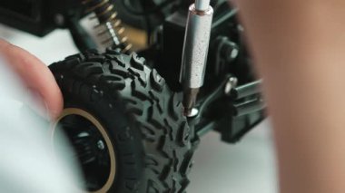 Genç öğrenciye yakın çekim tornavida kullanarak fındığı sıkılaştır. BTMM sınıfındaki robotik makine inşaatını incelerken araba modelini tamir eden ya da tamir eden beyaz bir genç. Eline odaklan. Öğretim