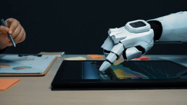 Gelecekçi bir robotik el, parlak ofis alanındaki renkli grafikleri gösteren dijital bir tabletle etkileşime girer, teknolojinin ve modern çalışma uygulamalarının füzyonunu vurgular. Noogenesis