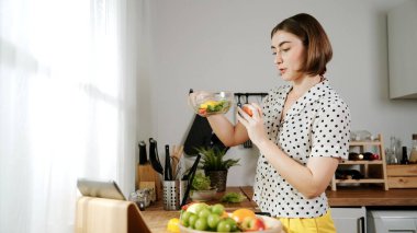 Kafkaseli anne kahvaltıda sebze pişirirken mutlu anne de modern mutfakta salata için taze malzemeler hazırlıyor. Hizmetçi sağlıklı yemek pişiriyor. Dikkat konsepti. Pedagoji.