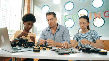Yetenekli öğretmen çeşitli öğrencilere kablo ve elektronik ekipman kullanarak araba modelini tamir etmeyi öğretiyor. Bilgisayara bakarken ana kartı kontrol etmek için elektrikli alet kullanmayı öğrenen bir kız. Öğretim