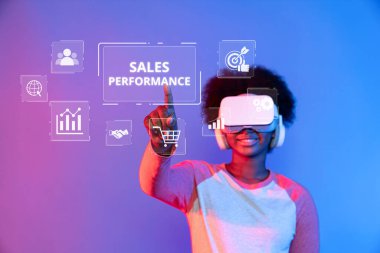 Genç bir kadın, canlı dijital pazarlama ortamında satış performans ölçümlerini gösteren sanal gerçeklik grafikleriyle etkileşim halindedir. XDMCP