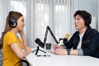 Gülümseyen radyo etkili sunucusu kulaklık takıyor kadın konuşmacı ile röportaj yapıyor sosyal medya internet sitesinden dinleyicilere bilgi paylaşıyor stüdyo kaydında sabah canlı yayın kanalı. İnfobahn.