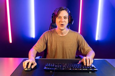 Kazanmak için çevrimiçi oyun oynayan akıllı flama makinesinin sunucu kanalı, neon ışıklı odada seçilen takım yarışması için izleyicilerle birlikte canlı yayında canlı yayında kulaklık takıyor. Bireysel.