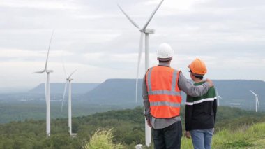 Oğluyla birlikte kırsal kesimdeki bir tepenin tepesinde ya da dağda bir rüzgar çiftliğinde mühendis. Yenilenebilir ve sürdürülebilir enerjinin gelecekteki üretimi için yenilikçi bir ideal. Rüzgar türbininden enerji üretimi.