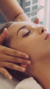 Lüks bir spa merkezinde masaj terapisti tarafından yüz masajı ve spa tedavisi için kaplıcaya uzanmış rahat bir kadın. Sağlık, stres atma ve gençleştirme kavramı.