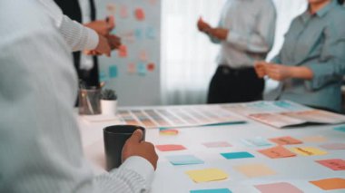 Çeşitli profesyonellerden oluşan bir grup, fikirleri paylaşmak ve modern ofis ortamında işbirliğini ilerletmek için renkli yapışkan notlar kullanarak canlı bir beyin fırtınası yapıyor. SACTR