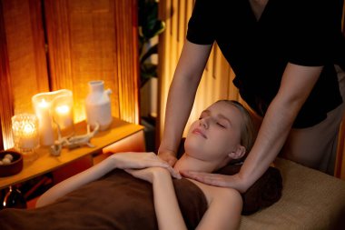 Beyaz kadın müşteri stres önleyici spa masajının keyfini çıkarıyor ve lüks otel ya da otelde sıcak mum ışığında güzellik teniyle eğleniyor. Sessiz.