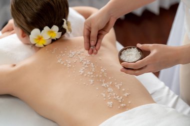 Lüks spa salonlarında sıcak mum ışığında cilt bakımı yaptıran kadın müşteri. Sağlık Spa vücut fırçasında tuz temizleme güzellik tedavisi. Sessiz.