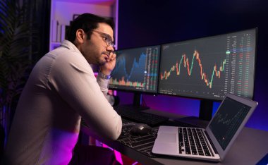 Akıllı tüccar işadamı, karanlık oda gecesinde neon ışıklı ofisteki arama pazarında yüksek kârla ekranda bilgisayar ve bilgisayar üzerinde dinamik borsa yatırımları üzerinde yoğunlaşıyor. Tahmin et..