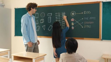 Genç Asyalı kız sınıfta dururken tahtada matematik formülü yazıyor. Çekici ilköğretim öğrencisi matematik dersinde çalışırken ya da soru cevap verirken. Eğitim konsepti. Pedagoji.