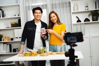 Aşçılar, sosyal medya yemek programı kanalı canlı yayın menü yemeği salatası, kepekli çörek ve video kameradan hamburger kaydı için telefonda yorum okuyorlar. İnfobahn.