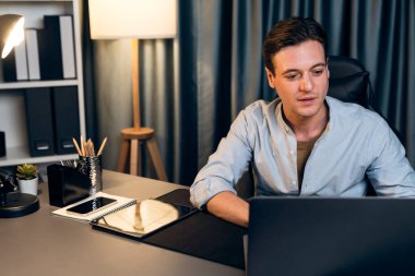 Akıllı iş adamı, gece vakti mavi perde arkasında iş hedefi olan finansal teknoloji veri raporlarını analiz etmek için veritabanı stoklarını araştırmak üzere dizüstü bilgisayarda uzaktan çalışıyor. Bireysel.