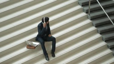 Merdivenlerde otururken kulaklıktan müzik dinleyen zeki bir iş adamı. Mutlu menajer dans ederken ya da müzikle uğraşırken gülümsüyor. Yatırımcı iyi haberler alıyor, terfi alıyor. Sevinçli..