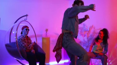 Çok kültürlü bir arkadaş kürsüde otururken Asyalı yetenekli bir dansçı modern müziğe geçiyor. Profesyonel dansçı, hipster takımı tezahürat yaparken ve desteklerken enerjik adımlar atıyor. Mutluluk.