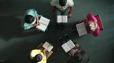 Çeşitli insanların el ele tutuşup İncil 'i kucağına alarak daireler çizerek oturmalarını. Sadık duaların havadan görünüşü el ele tutuşup Tanrı 'ya inançla, inançla dua etmek. Sempozyum.